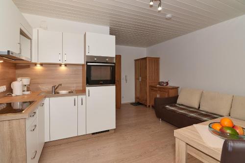 a kitchen and living room with white cabinets and a couch at Dangl GbR, Gästehaus Sonnenhof - inkl. Chiemgau Karte in Bergen