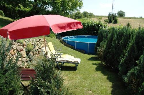 una sombrilla roja y sillas junto a la piscina en Chata Michaela, en Turnov