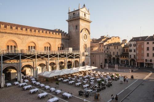 a building with a group of tables and a clock tower at Scaravelli Residenza in Mantova
