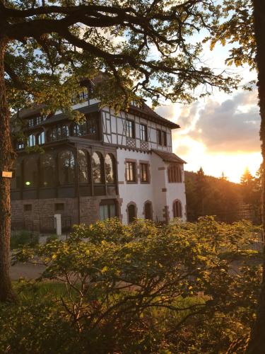 a large white house with the sun setting in the background at Logis Du Haut-Koenigsbourg in Thannenkirch