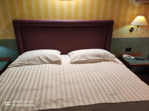 a bed with white sheets and pillows in a room at Val Del Rio in Fiumalbo