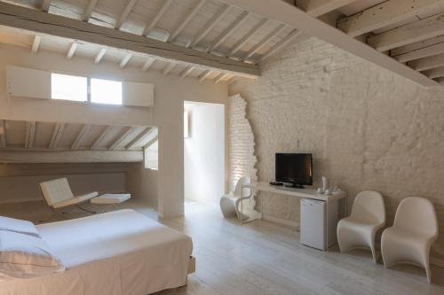 a white bedroom with a bed and a tv and chairs at Scaravelli Residenza in Mantova