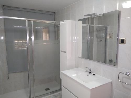La salle de bains blanche est pourvue d'un lavabo et d'une douche. dans l'établissement Apartamentos La Rosa - Calamocha, à Calamocha