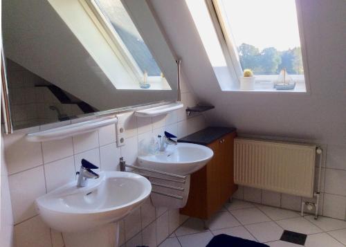 ein Badezimmer mit zwei Waschbecken und zwei Fenstern in der Unterkunft Ferienwohnung am Mühlendamm in Lastrup