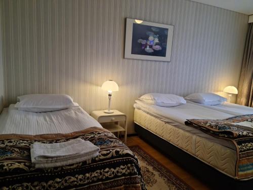 a hotel room with two beds and a picture on the wall at Hotelli Sandels in Siilinjärvi
