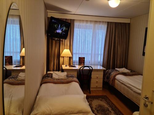 a hotel room with two beds and a television at Hotelli Sandels in Siilinjärvi