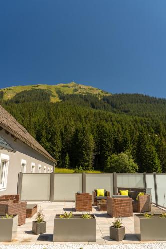 a patio with chairs and tables with a mountain in the background at Pension Polsterrinne in Vordernberg
