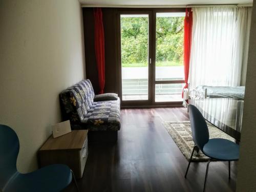 ein Wohnzimmer mit einem Sofa, Stühlen und einem Fenster in der Unterkunft Hannover Messe Wohnung 2 in Hannover