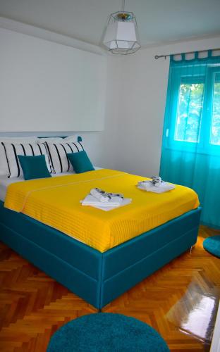 a bedroom with a blue and yellow bed with blue curtains at Agape C-52 in Trebinje
