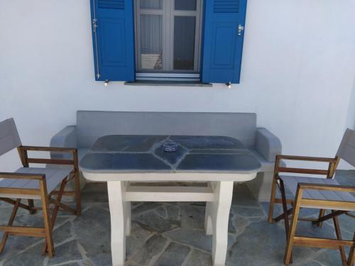 una mesa blanca con 2 sillas y una ventana en Cycladic houses in rural surrounding, en Amorgós