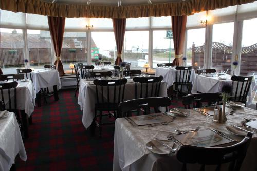 a dining room with tables and chairs with white table linens at The Upper Largo Hotel & Restaurant in Lundin Links
