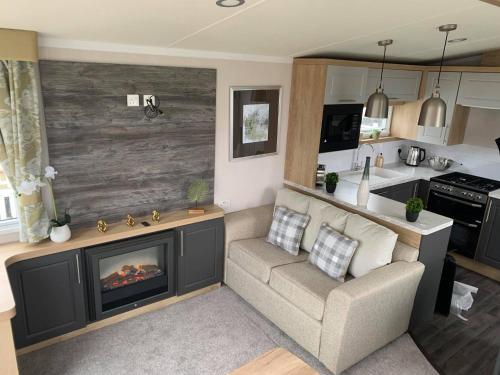 a living room with a couch and a fireplace at 3 bed presitage caravan Doniford Bay in Watchet