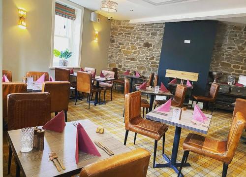 ein Restaurant mit Tischen und Stühlen und rosafarbenem Papier darauf in der Unterkunft Tredegar Arms Hotel in Tredegar