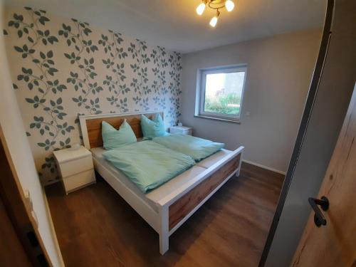 Schlafzimmer mit einem Bett mit grüner Bettwäsche und einem Fenster in der Unterkunft Ferienwohnung Karussell in Siebenbach