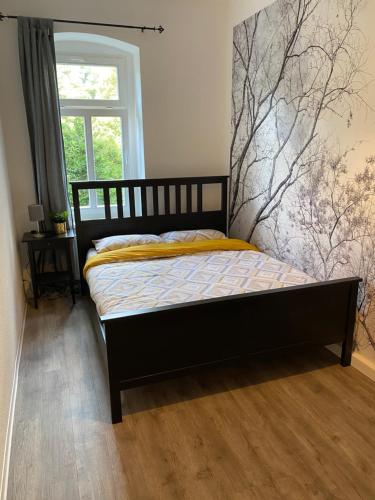 ein Schlafzimmer mit einem Bett mit einem Baumbild an der Wand in der Unterkunft Leutzsch apartment in Leipzig