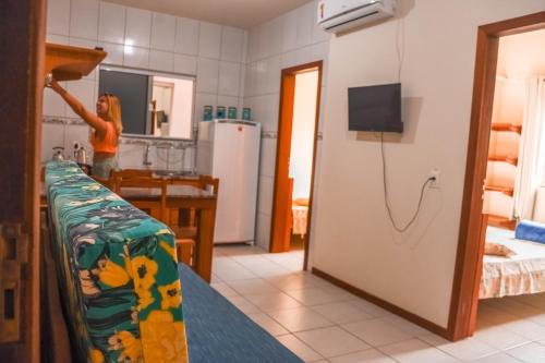 a woman standing in a kitchen with a refrigerator at Pousada Pegadas na Areia in Palhoça