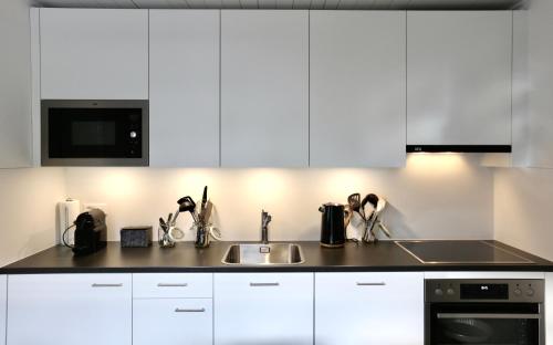 a kitchen with white cabinets and a sink at ALP APARTMENTS centre location with traditional design and self check-in in Engelberg
