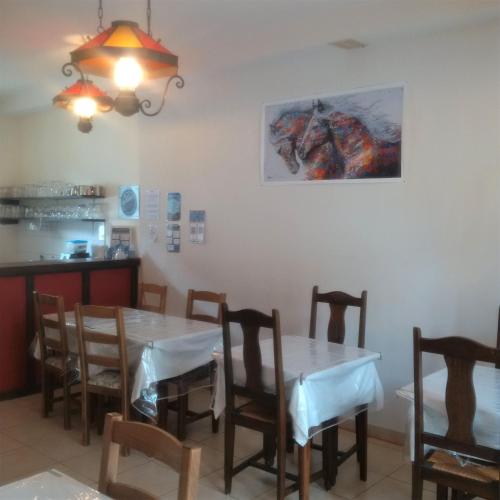 a dining room with a table and chairs with a picture on the wall at Le Relais des Cavaliers in Villeneuve-dʼEntraunes