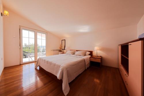 a bedroom with a large bed and a large window at Apartment and Rooms Santini in Sveti Filip i Jakov