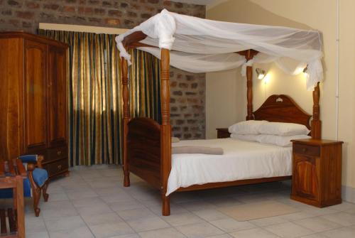 a bedroom with a canopy bed with white sheets at Seeheim Hotel in Seeheim