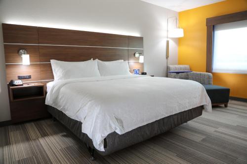 a hotel room with a large bed and a chair at Holiday Inn Express & Suites - Wylie West by IHG in Wylie