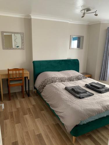 a bed with a green headboard in a bedroom at Relaxing home - 7-10min to Bournemouth sandy beach by car - private garden, parking and spa in Bournemouth