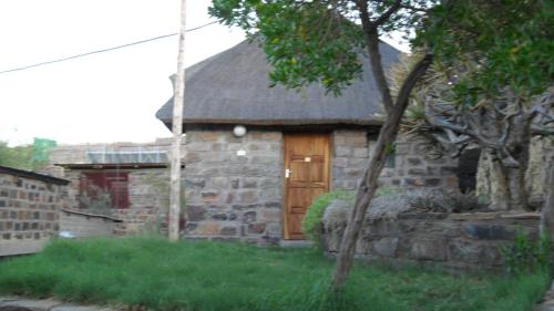 a stone house with a wooden door in a yard at Seeheim Hotel in Seeheim