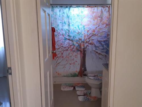 ein Badezimmer mit einem Duschvorhang und einem WC in der Unterkunft Bing's Home Away From Home in Ocho Rios