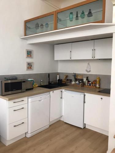 une cuisine avec des armoires blanches et un micro-ondes dans l'établissement Cosy apartment Vieil Antibes, à Antibes