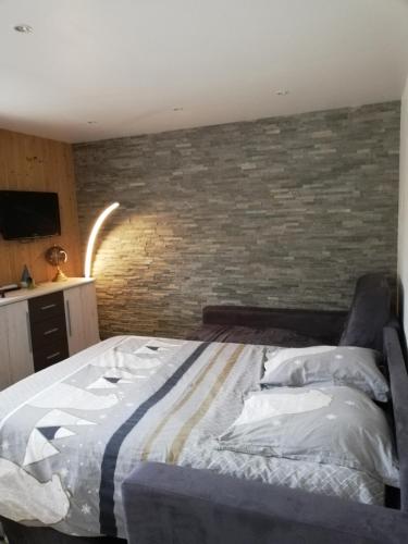 un lit dans une chambre avec un mur de briques dans l'établissement la Télécabine studio 4 personnes, à Marnaz