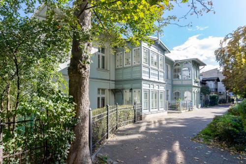 a large white and green house with a fence at Kierunek Sopot Apartament WERANDA Haffnera 32 in Sopot