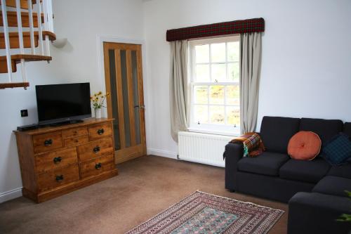 a living room with a couch and a television at Pirn Mill Self Catering Cottage in Cladich