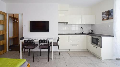 a kitchen with white cabinets and a table and chairs at Apartman Nikola Trojanovice in Trojanovice