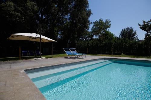 einen Pool mit 2 Stühlen und einem Sonnenschirm in der Unterkunft Hotel Villa Ciconia in Orvieto