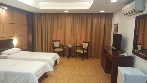 ALWAFA HOTEL FLATS في رِوي: غرفة فندقية بسريرين وطاولة وتلفزيون
