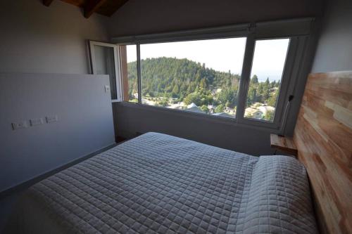 a bedroom with a bed and a large window at "Corazon al sur" departamento con vista única al Huapi in San Carlos de Bariloche