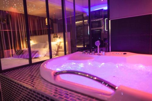 a bathroom with a tub with a bedroom in the background at L'Espace Privé Rouen in Rouen