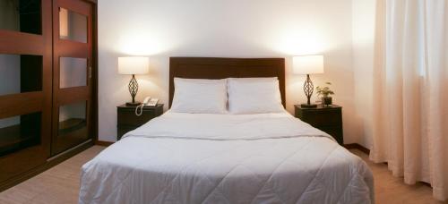 a bedroom with a large white bed with two lamps at Hotel Marcoantonio - Moyobamba in Moyobamba