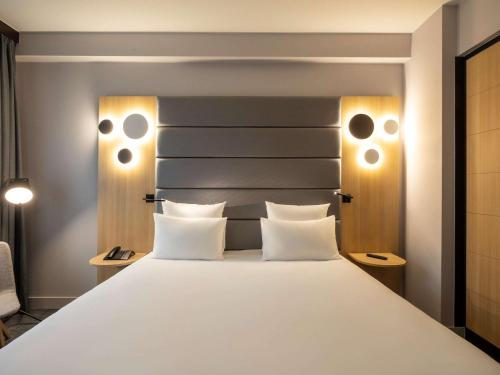 a bedroom with a large white bed with two pillows at Novotel Brussels Centre Midi in Brussels