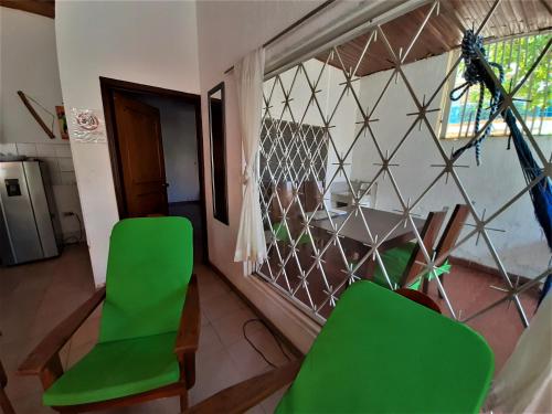 a living room with green chairs and a glass wall at Condominio El Portal Casa 1 in Carmen de Apicalá