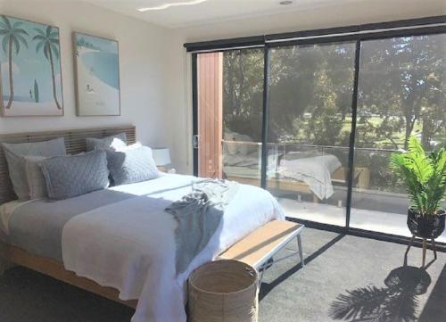 a bedroom with a large bed and a large window at Modern home in the heart of Mornington in Mornington