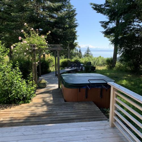 a hot tub on a wooden deck with a fence at Forest by the Sea Rentals in Merville