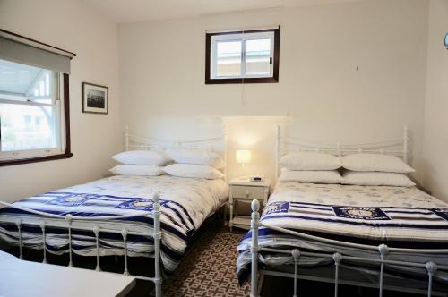 two twin beds in a room with a window at Bluey's in Queenscliff