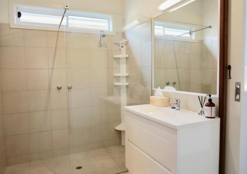 een badkamer met een douche, een wastafel en een spiegel bij Bluey's in Queenscliff