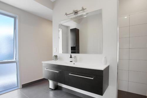 a bathroom with a sink and a mirror at Sky Blue Retreat - Waihi Beach Holiday Home in Waihi Beach