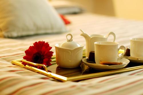 a tray with tea sets and a red flower on a bed at Belcolle, il bello della tranquillità in Chiavenna