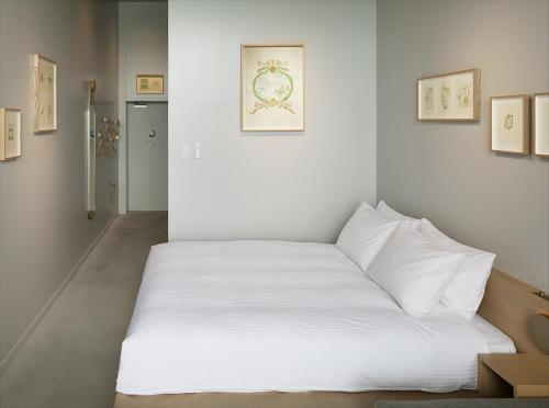 a bed in a room with white sheets at HOTEL ANTEROOM NAHA in Naha