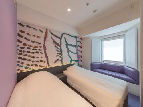 a room with two beds and a couch and a window at Hotel Art Stay Naha Kokusai-Dori in Naha
