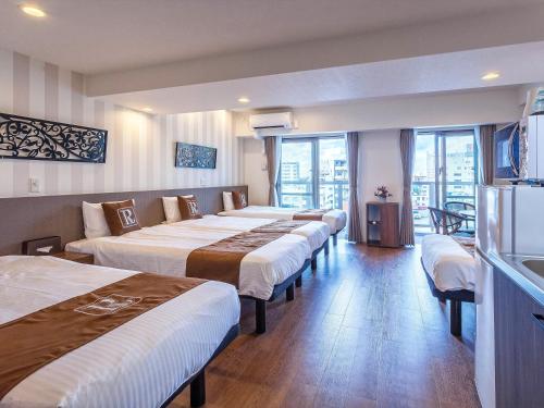 a row of beds in a hotel room at Living Inn Asahibashiekimae Premier in Naha