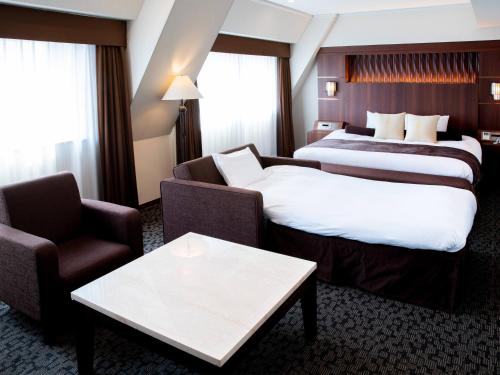 a hotel room with two beds and a couch and a table at Hotel Bellclassic Tokyo in Tokyo